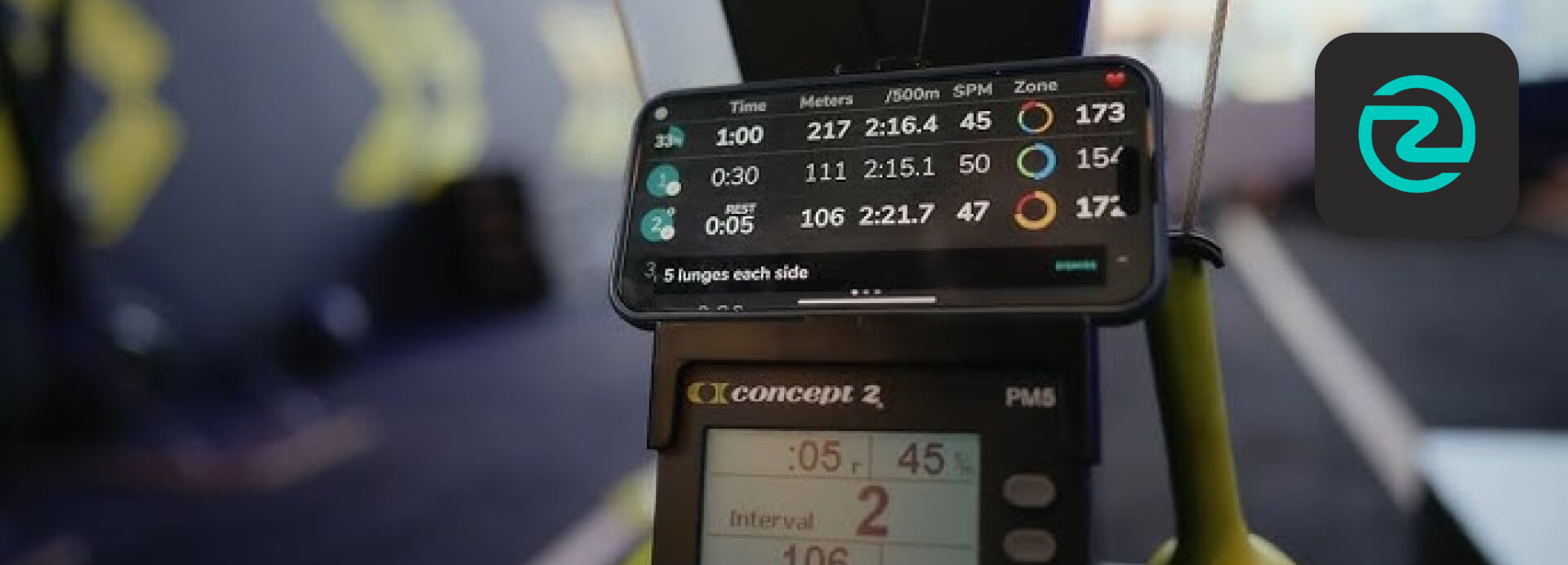 ErgZone rowing workout app displaying interval training data above a Concept2 PM5 monitor