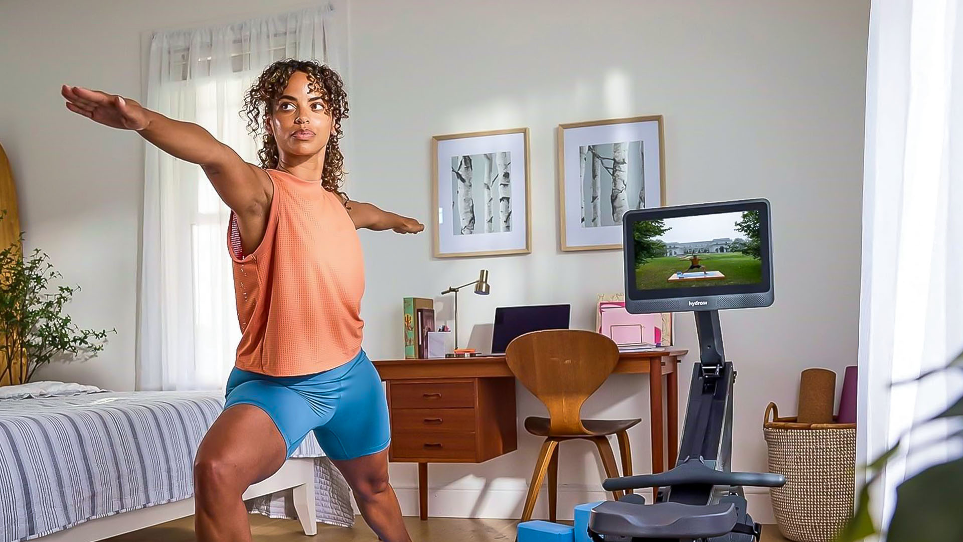 Woman doing warm-up exercises next to rowing machine in living room.