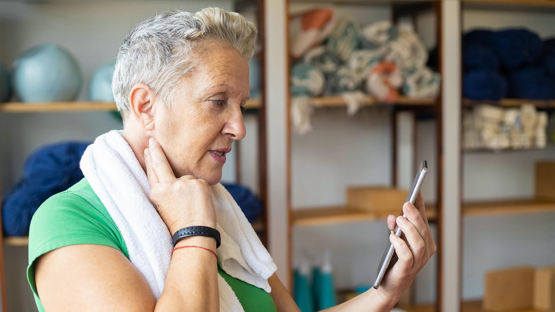 woman in workout clothes feeling her pulse and checking her phone.