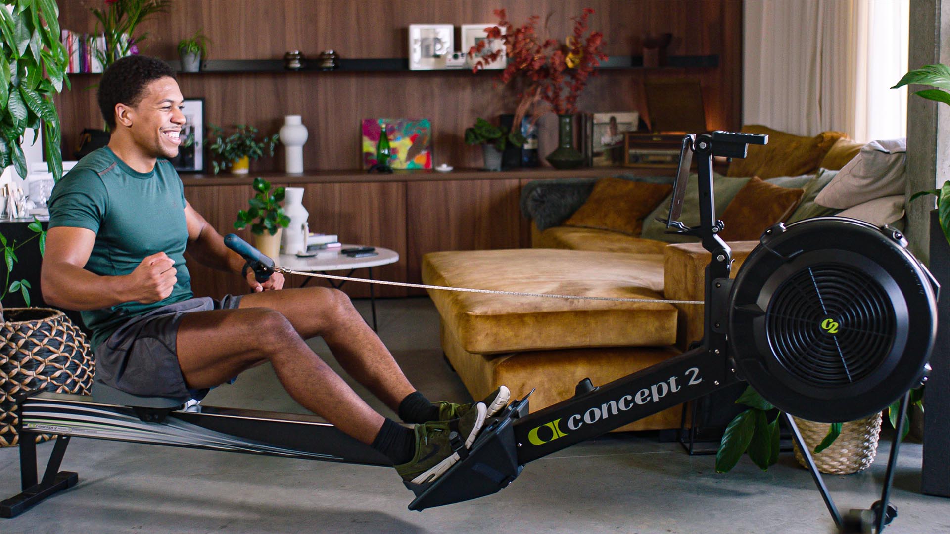 Man training in his living room with a rowing machine running EXR.