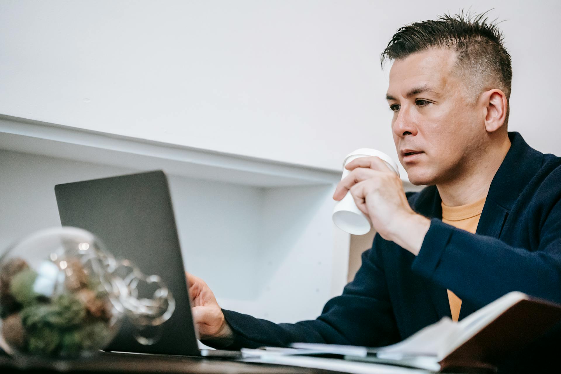 Coach sitting behind a computer drinking coffe while analyzing training data.