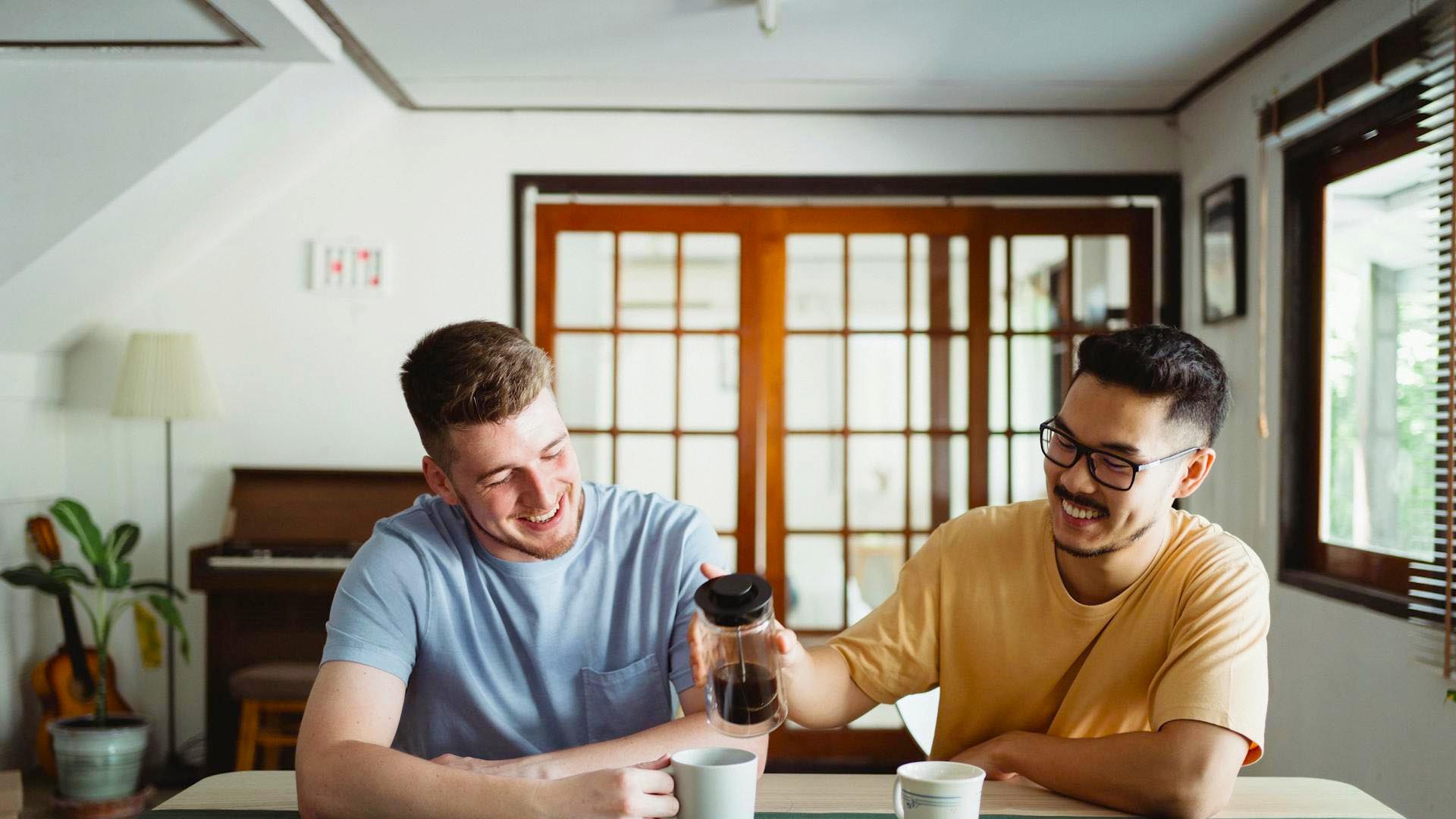 Two men drinking coffee and laughing.