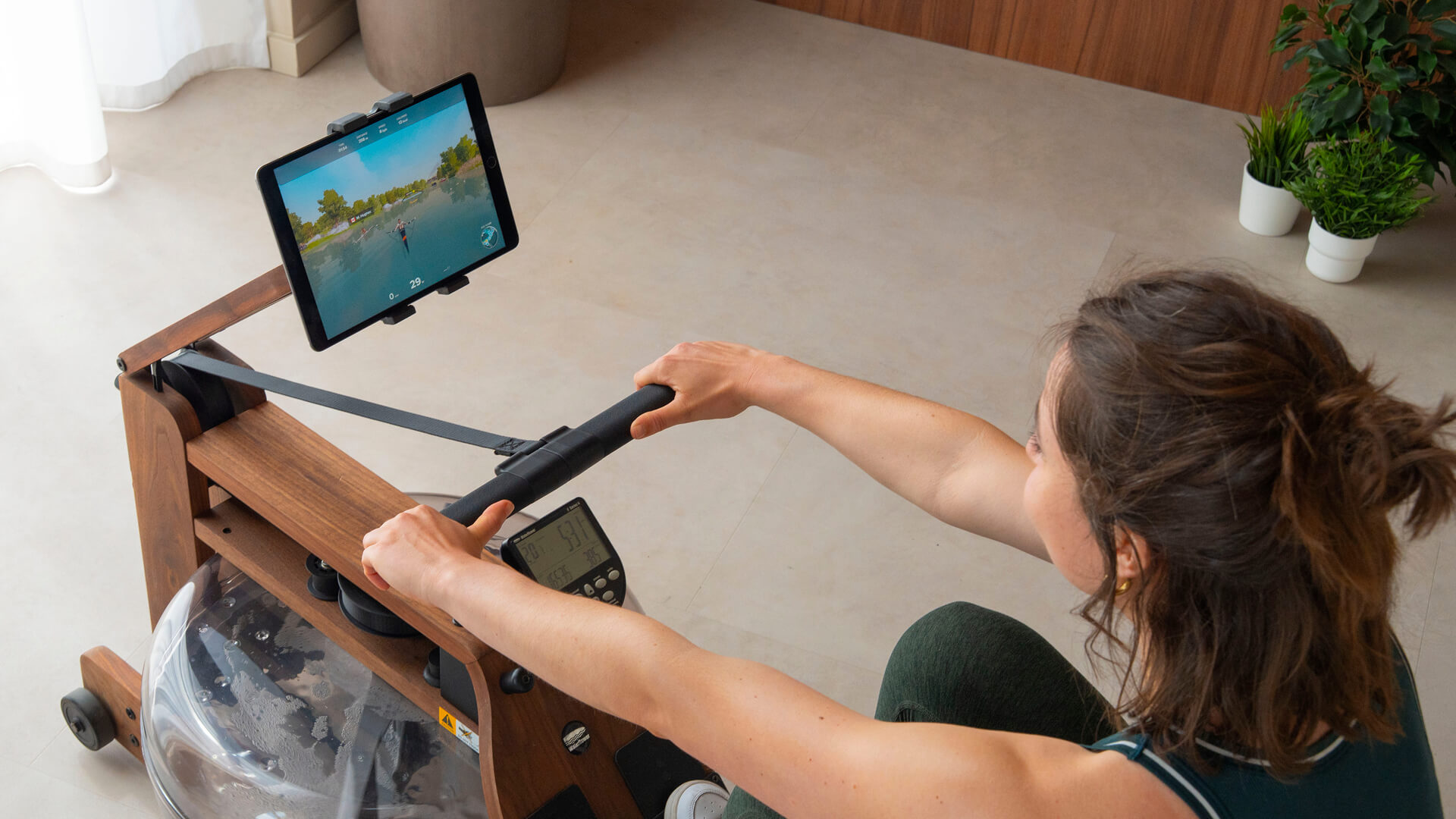 Person rowing on an indoor rowing machine in a calm, well-lit space during a low-impact recovery session
