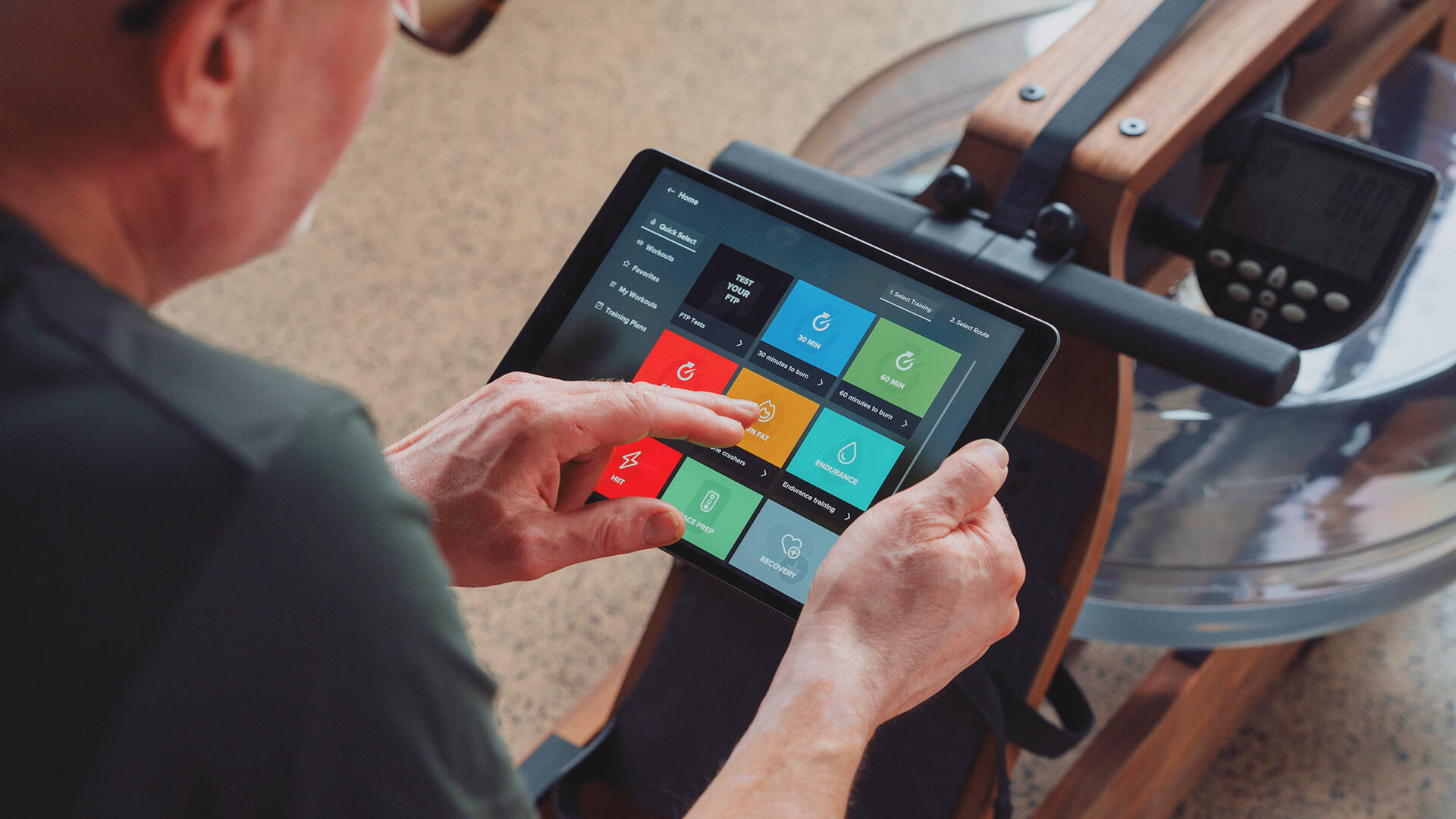 Person rowing at home while following a virtual EXR training session on a screen