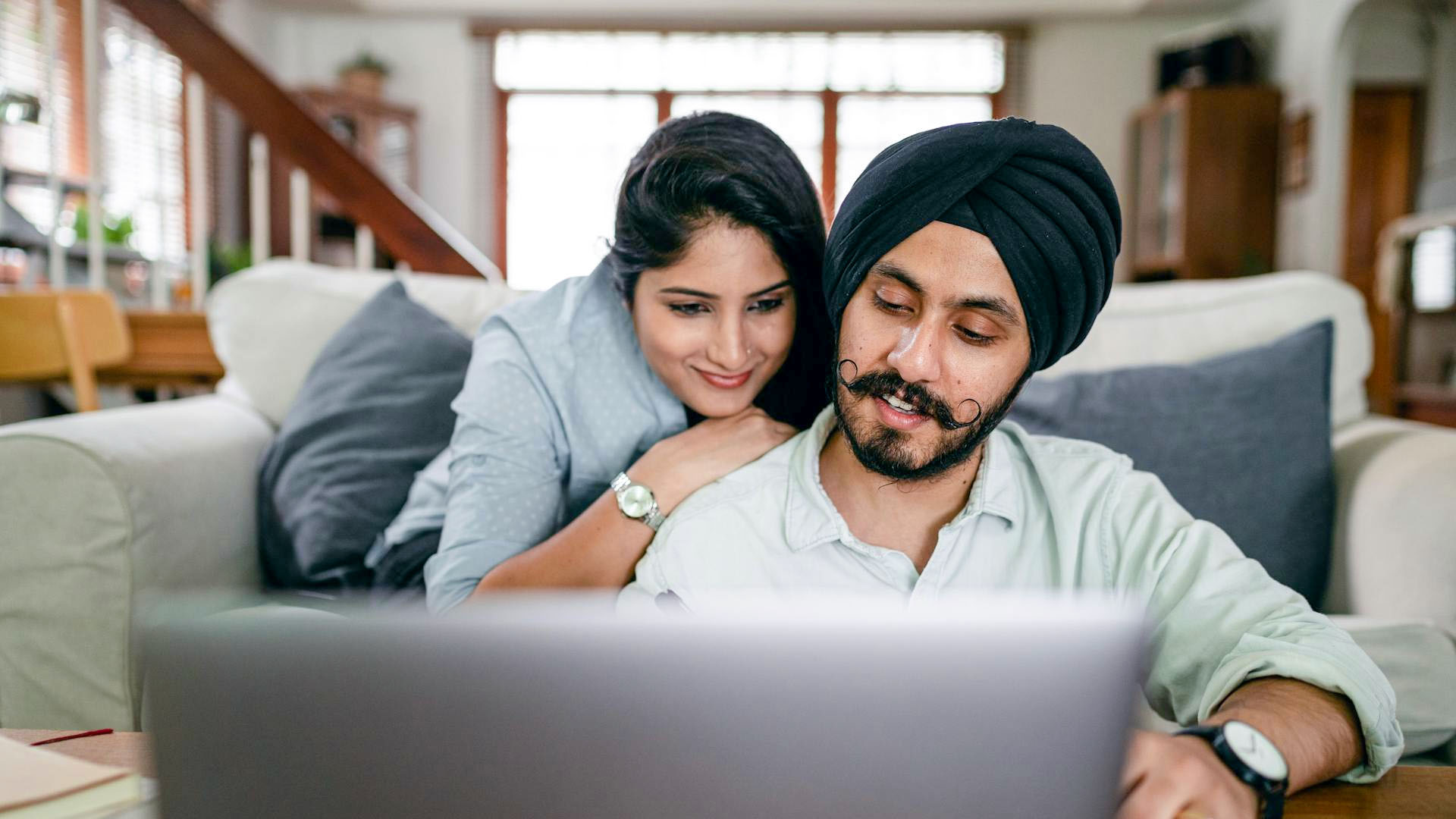 A couple looking at their tablet with a smile because they are online shopping.