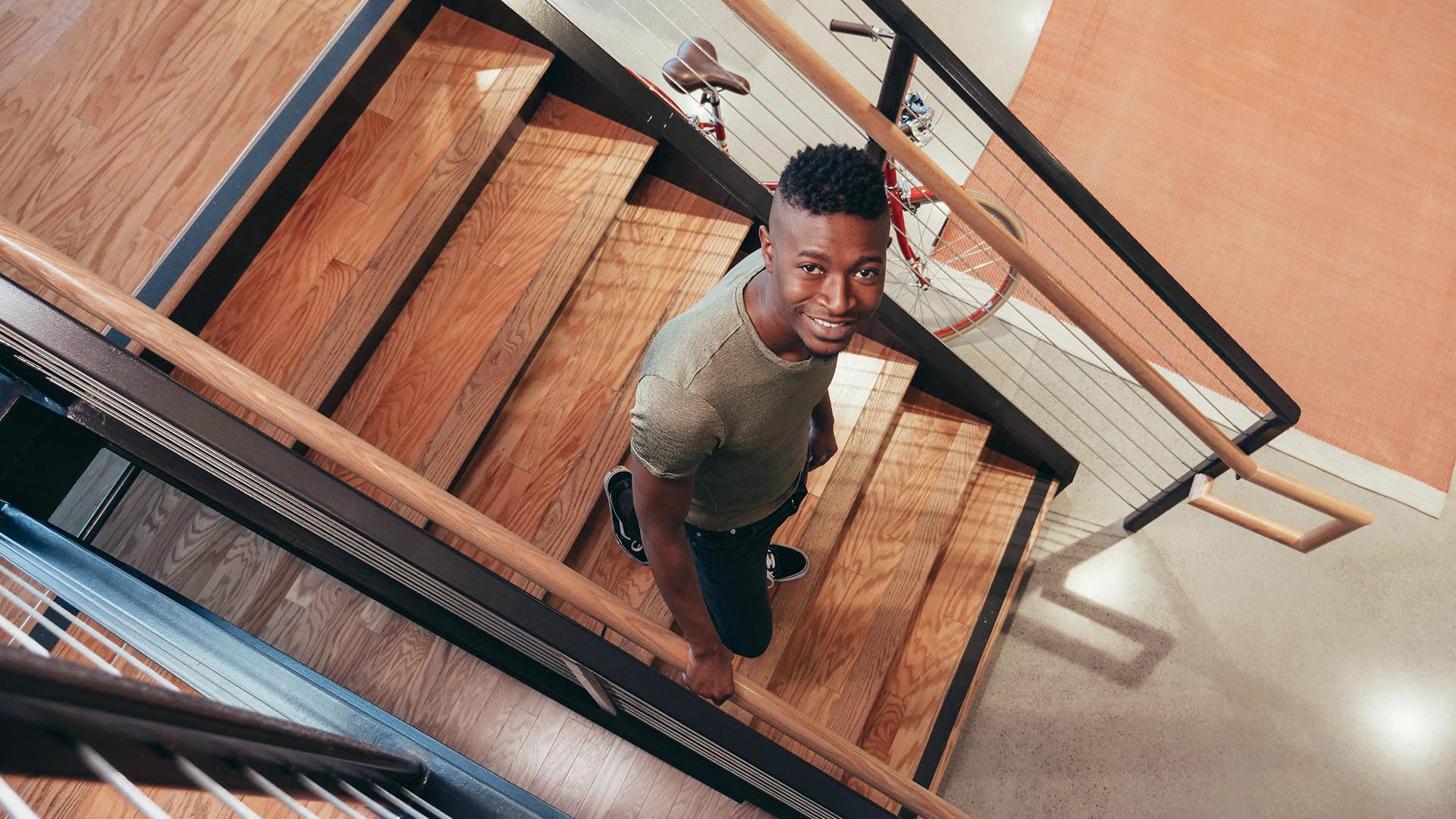 Man walking down the stairs at home while he looks up into the camera.