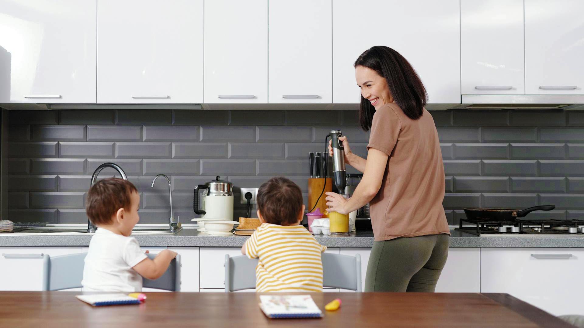 A woman prepares her workout nutrition together with her kids in the kitchen.