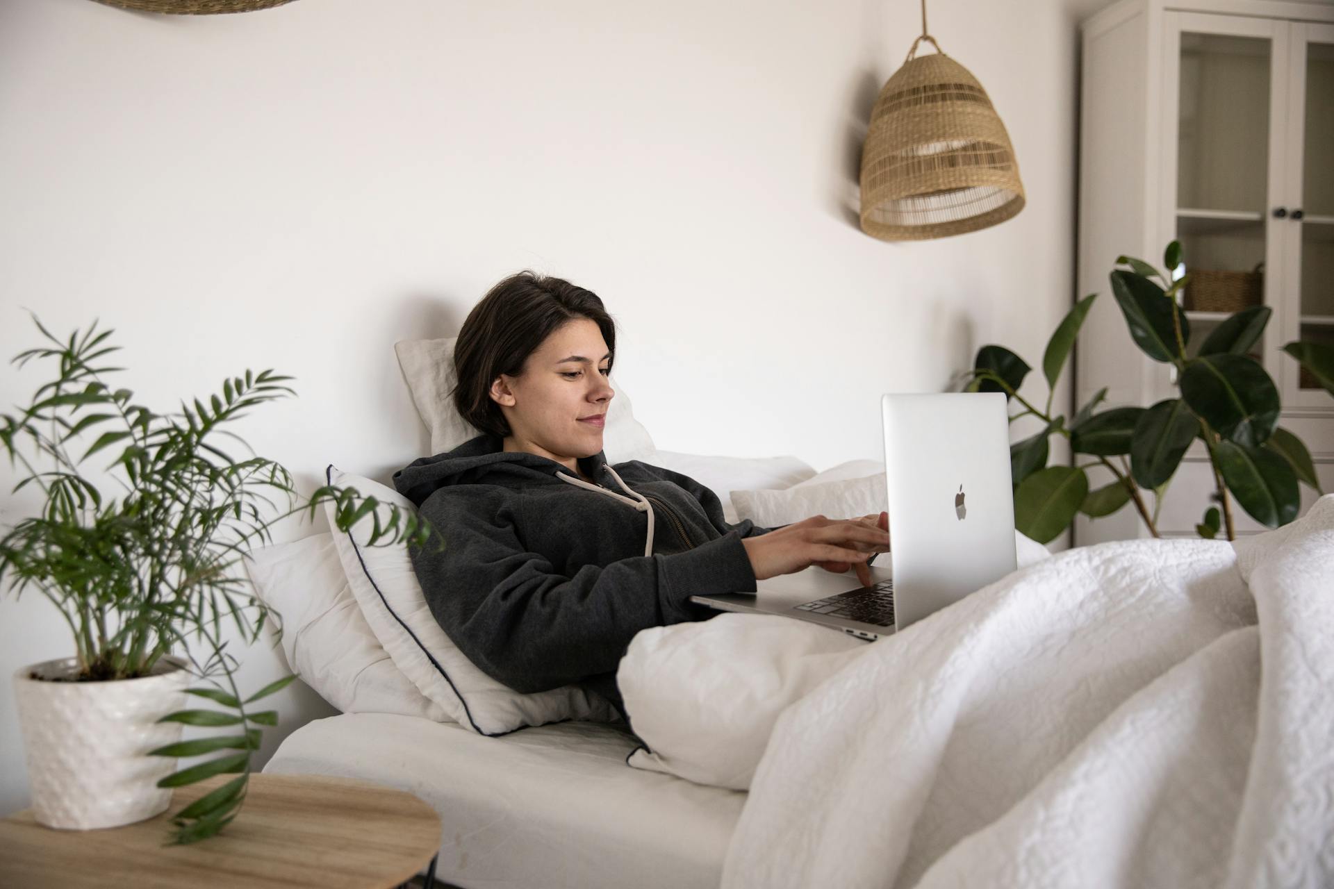 Woman resting in bed with her laptop.