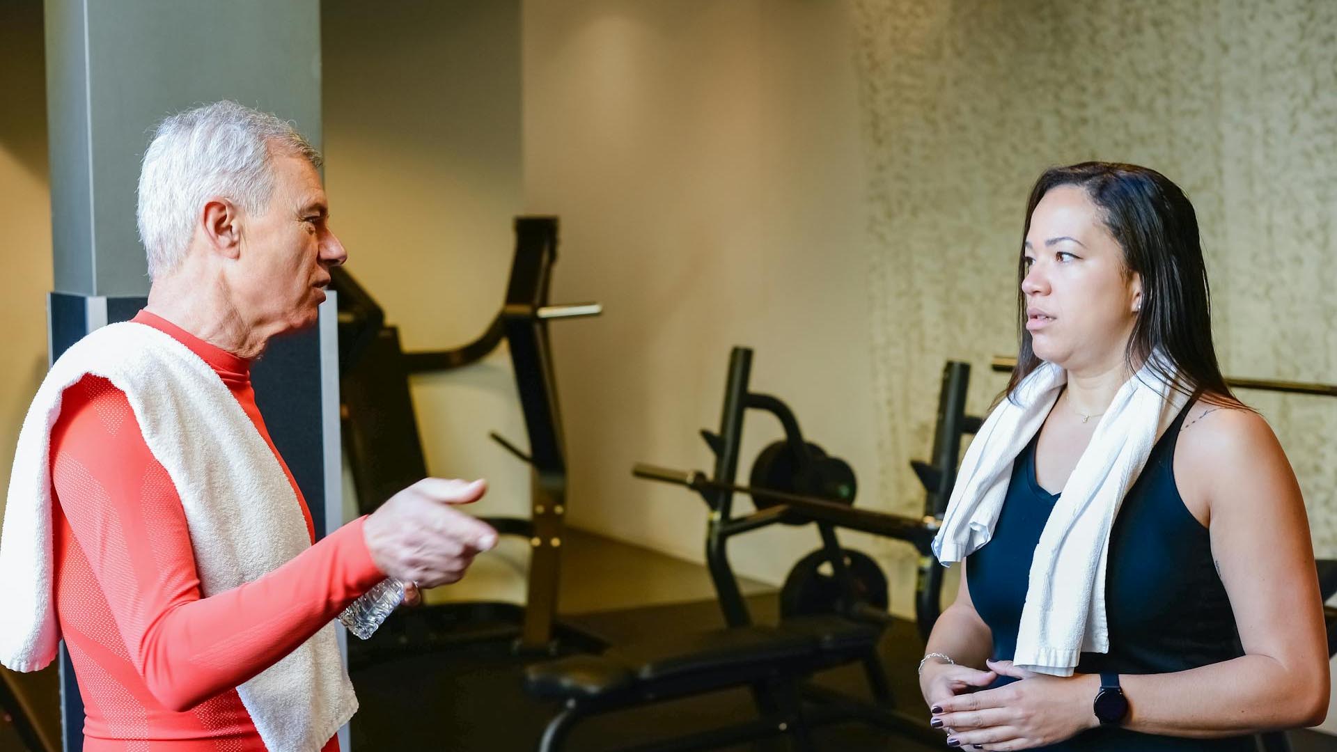 An old man and a young woman speaking at the gym.